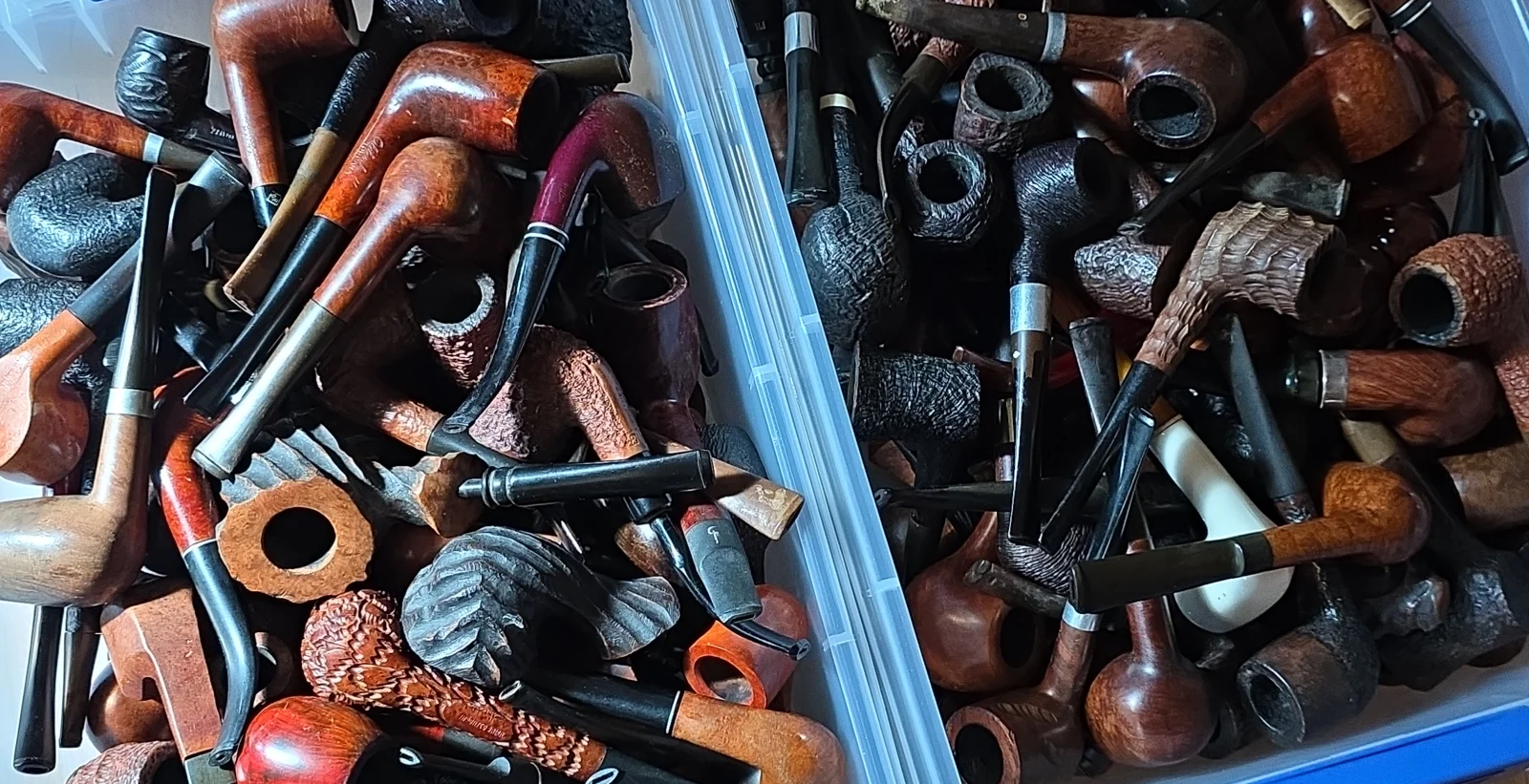 Two storage bins filled with mixed used tobacco pipes