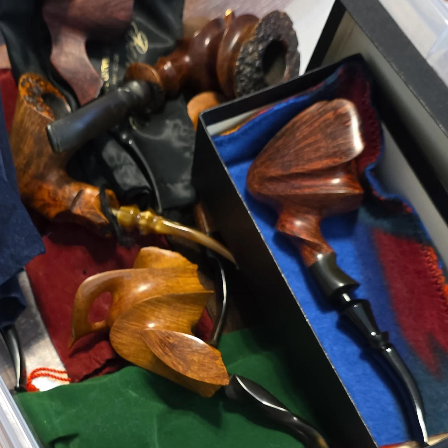Freehand pipes, cloth pipe pouches and a boxed pipe inside a storage bin